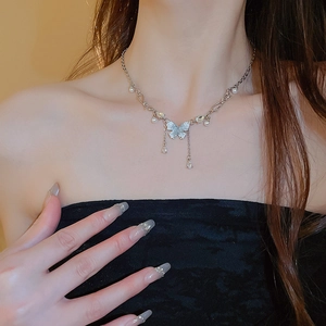 Dettaglio della collana a farfalla d'argento con nappe di cristallo e perle sul collo
