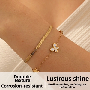 Detail of gold double-layered bracelet with a white mother-of-pearl butterfly charm