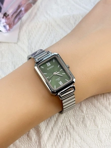 Detail view of square green watch with silver bamboo bracelet on woman's wrist