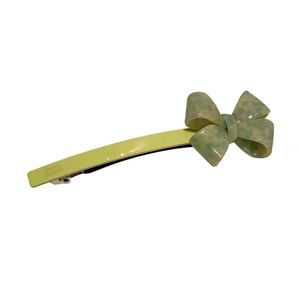 Elegant yellow acetate hair clip featuring a stylish green bow pattern on white background