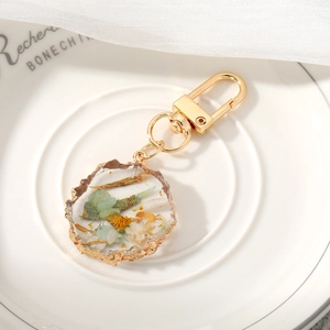 Detail of handmade resin keychain with real dried flowers and gold foil accents