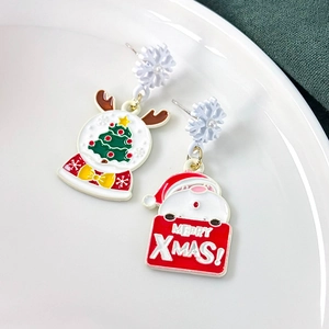 Detail of asymmetric Christmas earrings with Santa and Xmas tree in enamel finish