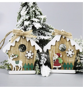 Detail of wooden Christmas house pendants with reindeer and Santa Claus on snow-covered tree