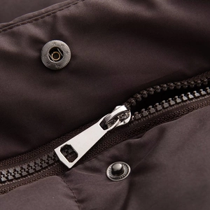 Macro detail of dark brown waterproof jacket with metal zipper and snap button closure