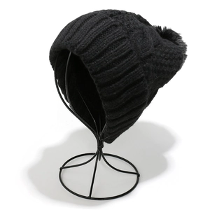 Close-up of black chunky knit beanie featuring a cable pattern and fluffy pom-pom detail
