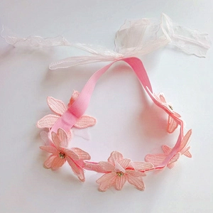 Dettaglio fascia per neonata in pizzo rosa con fiori di strass e nastri regolabili