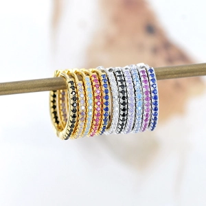 Macro shot of colorful zircon pavé huggie hoop earrings in gold and silver finish