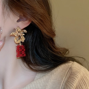 Detail of flower stud earrings with red Chinese double happiness tassel on model
