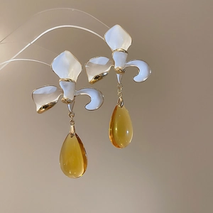 Detail of white flower stud with amber teardrop pendant and elegant golden edges