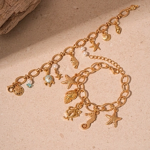 Gold ocean charms bracelet with starfish and seahorse on natural stone background