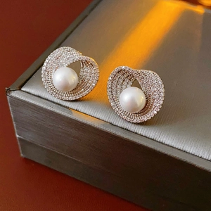 Gros plan de boucles d'oreilles en perles avec bordure en zircon sur un écrin