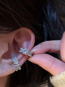 Detail of silver ear bone clips set with white zircon stones worn on the ear