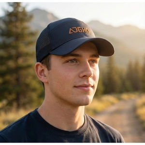 Close-up of a breathable mesh trucker hat with orange logo embroidery in outdoor setting
