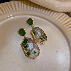 Detail of irregular hollow emerald earrings with gold plating and resin geode texture