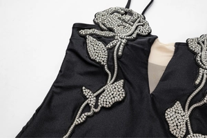 Detail of silver rhinestone floral patterns and mesh splicing on black one-piece swimsuit