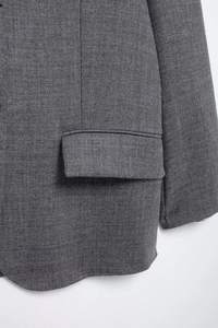 Detailed close-up of dark grey blazer fabric showing texture and stitching quality