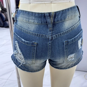 Vue détaillée du dos d'un short en jean montrant le délavage vintage et les poches déchirées