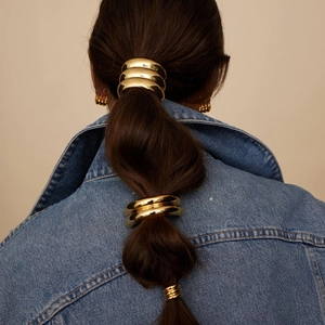 Close-up of three polished 18k gold stainless steel hair rings on a model pony tail