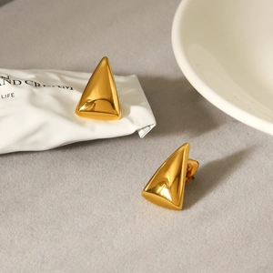Detailed view of polished gold triangle earrings on a soft felt textured background