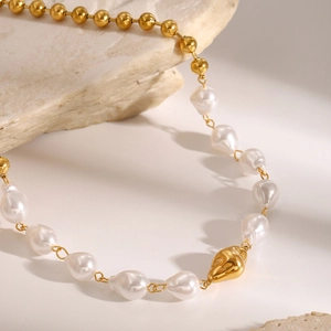 Detailed shot of golden stainless steel beads and white baroque pearls on a luxury necklace