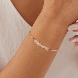 Minimalist gold snake chain bracelet with white natural stones worn on woman's wrist