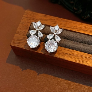 Gros plan de boucles d'oreilles fleurs étincelantes en zircone sur un support en velours