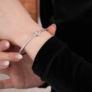 Detail of silver oval zircon bangle with rectangular side stones on woman's wrist