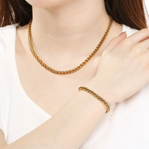 Ensemble collier et bracelet en maille épi dorée en acier inoxydable porté par un mannequin
