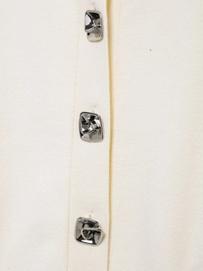 Detail of elegant cream knit cardigan featuring three unique silver flower metal buttons