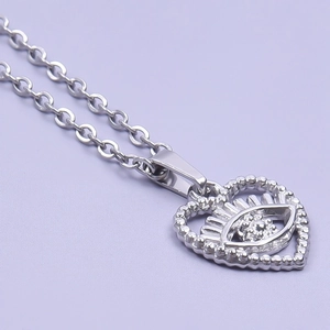 Macro shot of a silver heart pendant with an eye motif and sparkling zircon stones