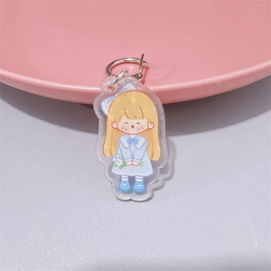 Detailed view of a cute acrylic cartoon girl keychain on a soft pink decorative plate