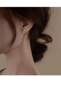 Close-up of minimalist S925 sterling silver four-point star stud earring worn by model