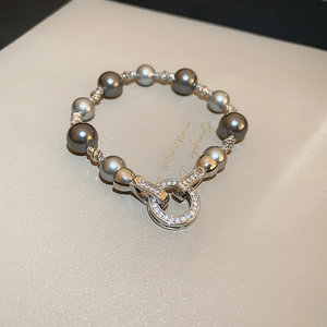 Makroaufnahme von grauen Perlenarmband mit kristallbesetztem Ringverschluss auf Tablett