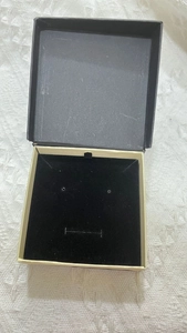 Detail of open flip jewelry box showing black velvet interior with earring and necklace slots