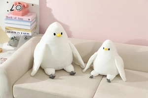Detail of two white plush pigeon toys with soft texture on a cozy beige sofa