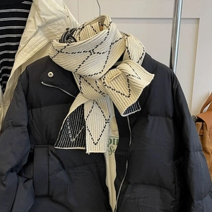 Detailed texture of a soft knitted scarf featuring black plaid and a handmade label