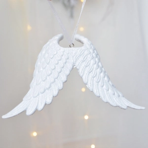 Elegant white resin angel wings Christmas ornament with white ribbon and warm bokeh lights