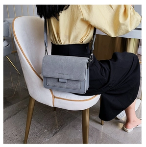 Side view of gray matte PU leather crossbody bag worn by a model in a casual setting