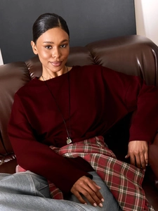 Detailansicht eines tiefroten Baumwoll-Langarmshirts auf einem Vintage-Ledersofa