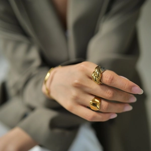 Detail of two-tone braided rope ring and irregular lava texture ring in polished finish