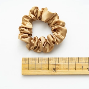Elastic satin scrunchie in champagne gold silk finish shown with centimeter measurement