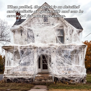 Outdoor Halloween giant white spider web with black spiders covering a classic house facade