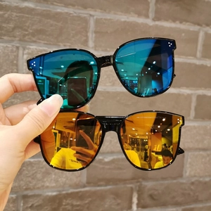 Close-up of kids sunglasses with three metal dots on black frames and colorful lenses
