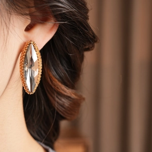 Detail of luxury marquise cut crystal earring with gold beaded border worn by a model