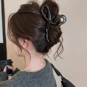 Glossy black shark hair claw clip in a streamlined twist design worn on a model back view
