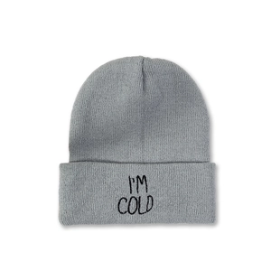 Detail of grey beanie showing dense knit texture and I'M COLD embroidery in black