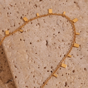 Macro shot of polished 18K gold plated rectangular pendants on a fine link chain necklace