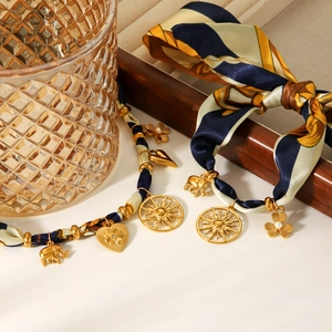 Detail of silk scarf necklace featuring golden elephant, sun and heart charms
