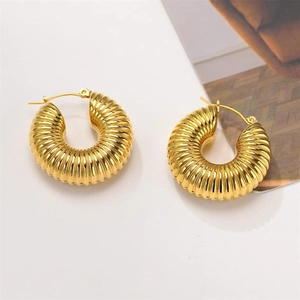 Detailed macro view of gold-plated croissant hoop earrings with ribbed texture and glossy finish