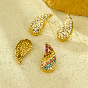 Macro shot of gold teardrop earrings with colorful zircon crystals on sandy stone